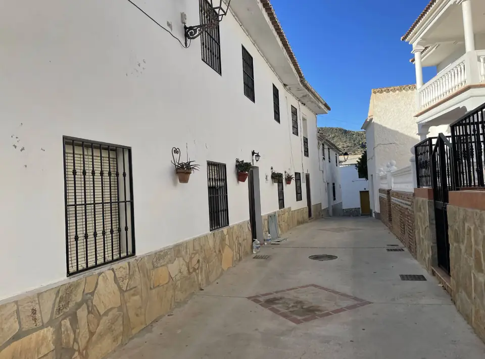 Calle encalada de Mondrón con rejas y macetas