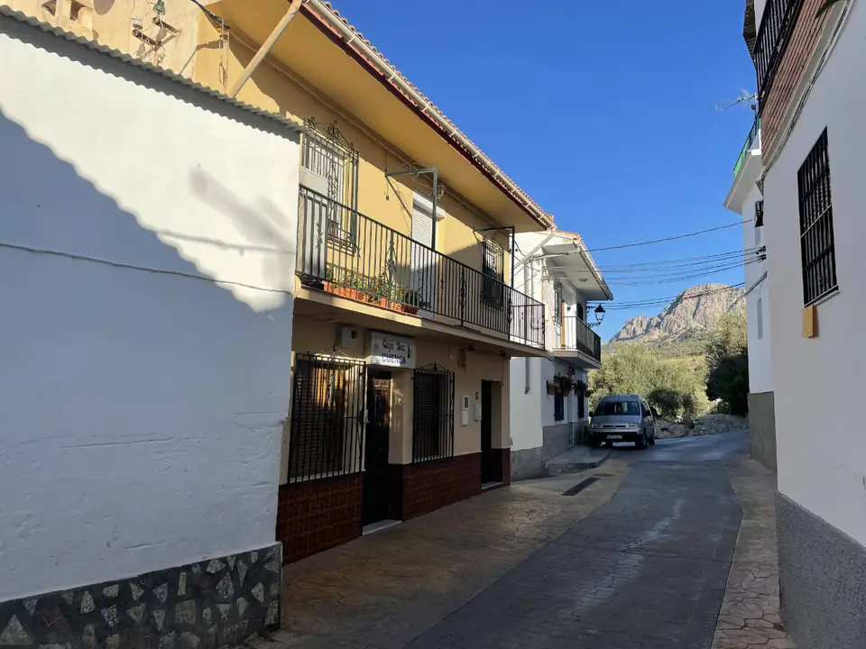 Calle de Mondrón con casas blancas y la sierra al fondo