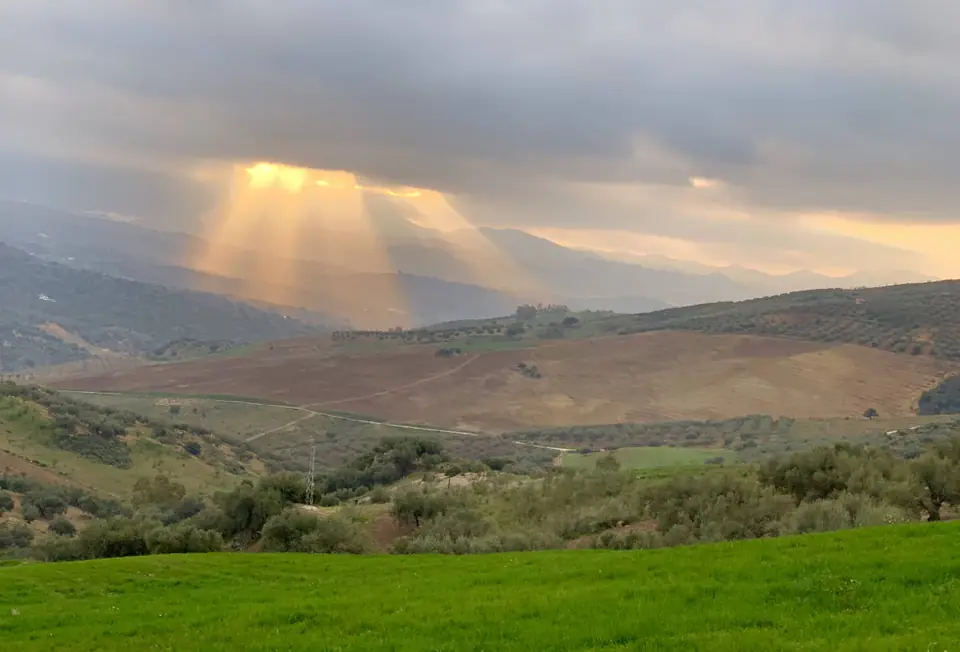 Rayos de sol entre las nubes sobre el valle y los olivares de Mondrón