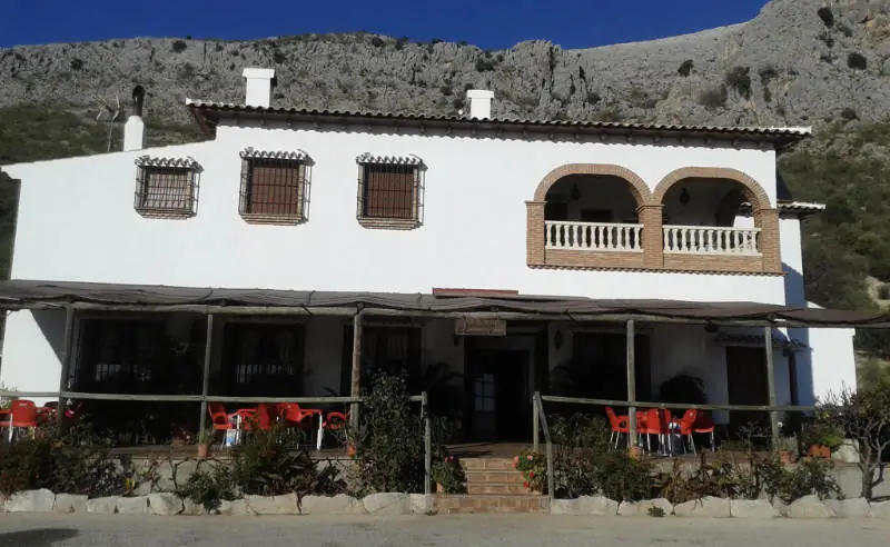 Fachada blanca y terraza de El Caserón de Guaro bajo la sierra